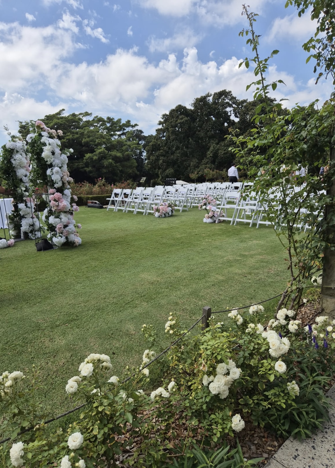 Wedding ceremony hire Sydney with white folding chairs setup for outdoor ceremony