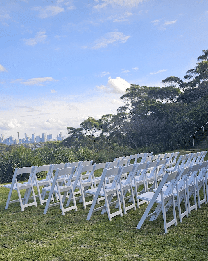 White folding chair wedding ceremony setup at Gunners Barracks Harbour View Lawn with Sydney Harbour skyline by Budget Event Hire Sydney